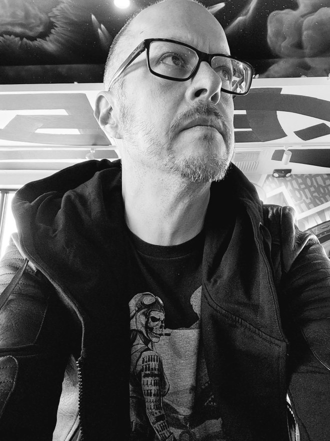 Dressed in a leather jacket hoodie and zombie pinup shirt, Mike stares pensively. As one can only do taking selfies in Dave's Hot Chicken.